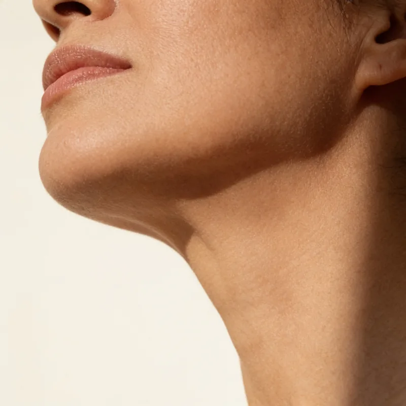Jaw underside and the line of the neck above an open linen collar.