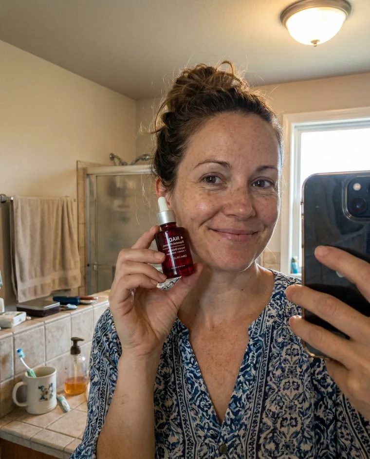 Stand-in photo: a person holding the serum bottle at home.